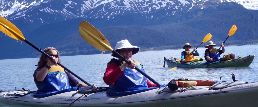Women's travel group kayaking on Alaskan lake