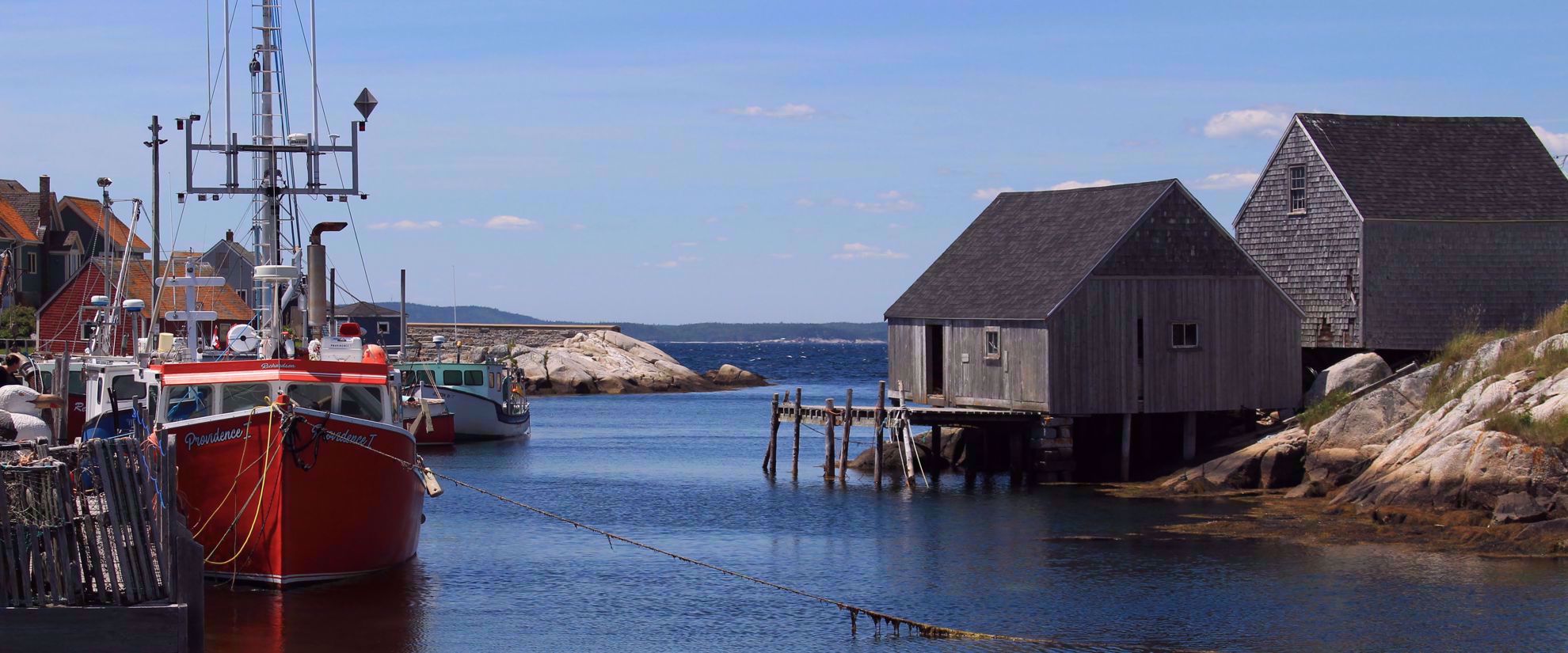 sailboat docked at harbor with wooden buildings