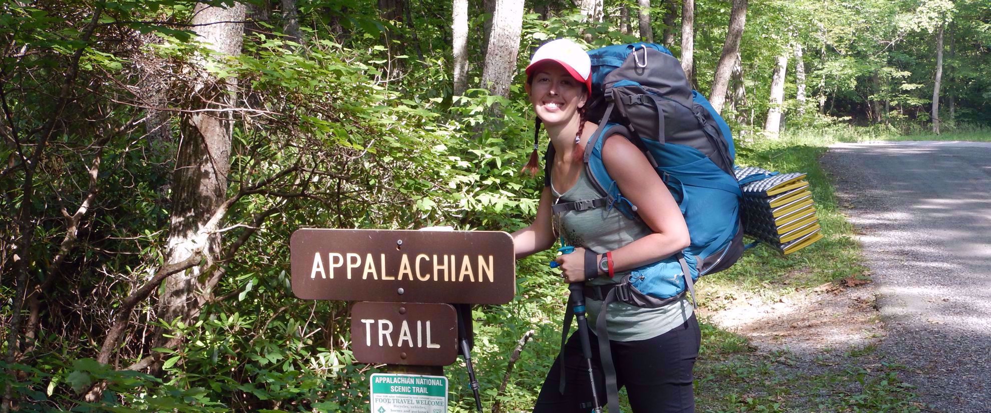 woman smiles by appalachian trail sign