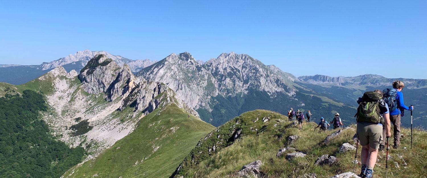 women hiking The Via Dinarical lush green mountains and bright blue skies