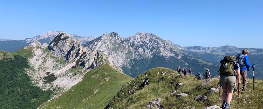 women hiking The Via Dinarical lush green mountains and bright blue skies